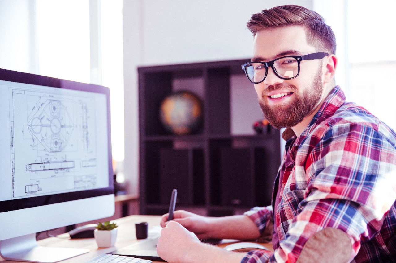 Portrait of happy handsome modern designer drawing blueprint on computer using pen tablet with stylus
